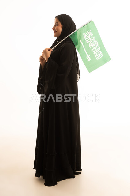 امرأة سعودية بالعباءة تحمل العلم السعودي خلفية بيضاء