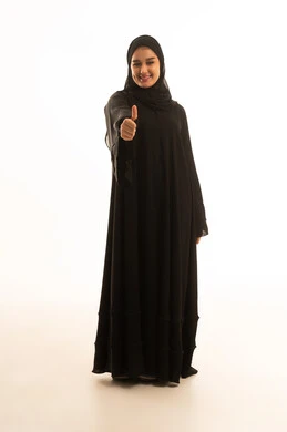 امرأة سعودية بعباءة سوداء تقوم بإيماءة الإبهام للأعلى