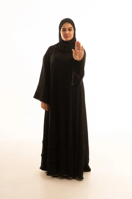 امرأة سعودية بالعباءة تقوم بإشارة التوقف خلفية بيضاء