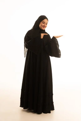 امرأة سعودية بالعباءة السوداء تشير بيدها خلفية بيضاء