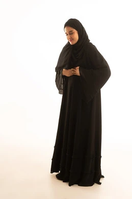 امرأة سعودية بالعباءة السوداء على خلفية بيضاء