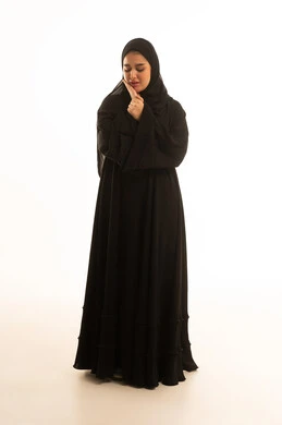 امرأة سعودية بالعباءة السوداء تفكر بخلفية بيضاء