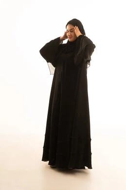 امرأة سعودية بالعباءة تعاني من الصداع بخلفية بيضاء