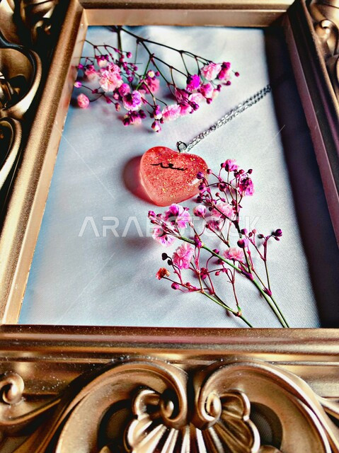 صورة مقربة لبرواز خشبي في داخله قطعة على شكل قلب مكتوب عليها سعد ، أزهار زينة بنفسجية اللون ، مناسبات سعيدة ، هدية 