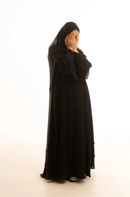 امرأة سعودية بالعباءة السوداء تغطي وجهها بخلفية بيضاء