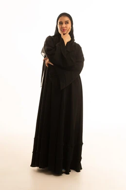 امرأة سعودية بالعباءة السوداء تفكر خلف خلفية بيضاء