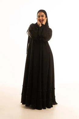 امرأة سعودية مبتسمة بالعباءة السوداء على خلفية بيضاء