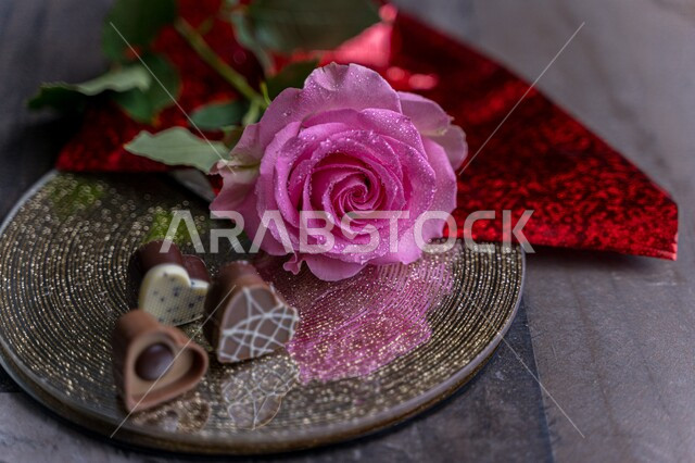 Close-up of a purple artificial rose, with chocolate beads on a plate, hospitality and reception, occasions and holidays, congratulations and blessings, social occasions