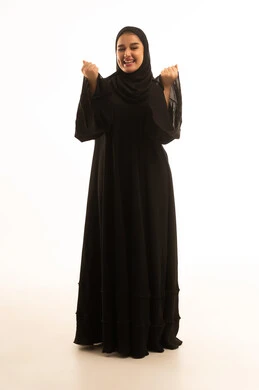 امرأة سعودية بالعباءة تحتفل أمام خلفية بيضاء