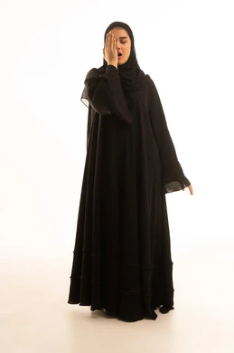 امرأة سعودية بالعباءة السوداء على خلفية بيضاء