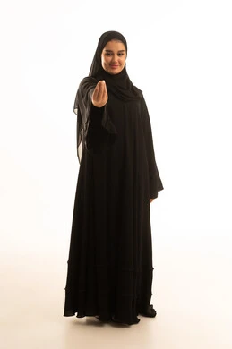 امرأة سعودية بالعباءة السوداء تقوم بإيماءة يد