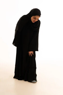 امرأة سعودية بالعباءة السوداء تمسك ركبتها من الألم