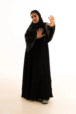 امرأة سعودية بالعباءة السوداء تقوم بإيماءة التوقف