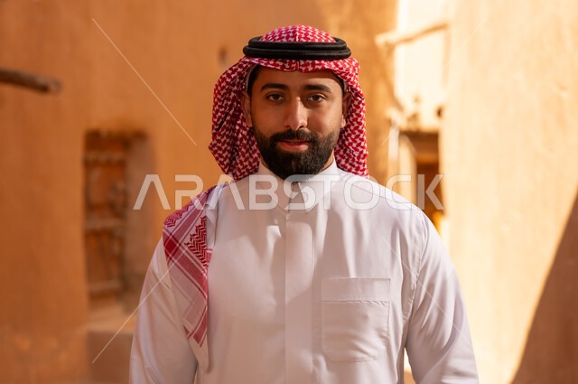 رجل عربي سعودي خليجي يرتدي الزي التقليدي ثوب أبيض وشماخ يقف بتعابير الثقة والجدية، ذكرى تأسيس الدوله السعوديه الاولى على يد الامام محمد بن سعود, يوم بدينا 22 فبراير 1727م, العمق التاريخي والحضاري للمملكة،الإحتفالات الوطنيه في المنطقه الوسطى