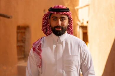 An Arab Saudi Gulf man wearing traditional attire, a white thobe and a shemagh, stands with expressions of confidence and seriousness, commemorating the founding of the first Saudi state by Imam Muhammad bin Saud, on the day we began, February 22, 1727 AD, the historical and cultural depth of the Kingdom, national celebrations in the central region.