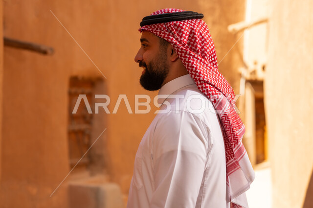 صورة من الجانب لرجل عربي سعودي خليجي يرتدي الزي التقليدي ثوب أبيض وشماخ الوقوف بثقة بالنفس، ذكرى تأسيس الدوله السعوديه الاولى على يد الامام محمد بن سعود, يوم بدينا 22 فبراير 1727م, العمق التاريخي والحضاري للمملكة،الإحتفالات الوطنيه في المنطقه الوسطى