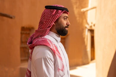 A side image of an Arab Saudi Gulf man wearing traditional attire, a white thobe and a shemagh, standing confidently. It commemorates the founding of the first Saudi state by Imam Muhammad bin Saud on February 22, 1727. The historical and cultural depth of the Kingdom, national celebrations in the central region.