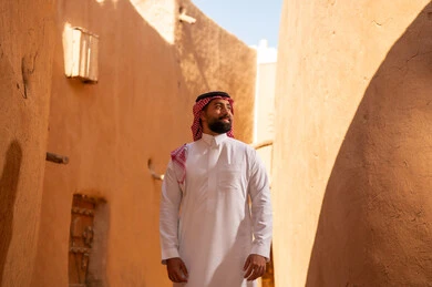 رجل عربي سعودي خليجي يرتدي الزي التقليدي ثوب أبيض وشماخ يقف بتعابير الثقة والجدية، ذكرى تأسيس الدوله السعوديه الاولى على يد الامام محمد بن سعود, يوم بدينا 22 فبراير 1727م, العمق التاريخي والحضاري للمملكة،الإحتفالات الوطنيه في المنطقه الوسطى
