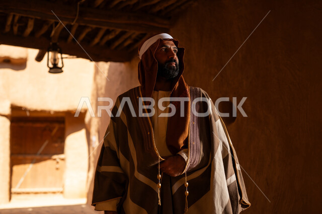 An Arab Saudi Gulf man wearing the founding day attire stands inside a mud building, commemorating the establishment of the first Saudi state by Imam Muhammad bin Saud, on the day we began, February 22, 1727. The historical and cultural depth of the Kingdom is the identity of Saudi National Day 92.