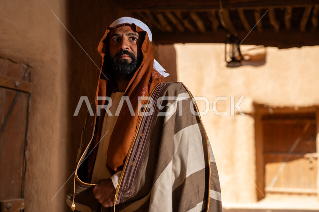 An Arab Saudi Gulf man wearing the founding day attire stands inside a mud building, commemorating the establishment of the first Saudi state by Imam Muhammad bin Saud, on the day we began, February 22, 1727. The historical and cultural depth of the Kingdom is the identity of Saudi National Day 92.