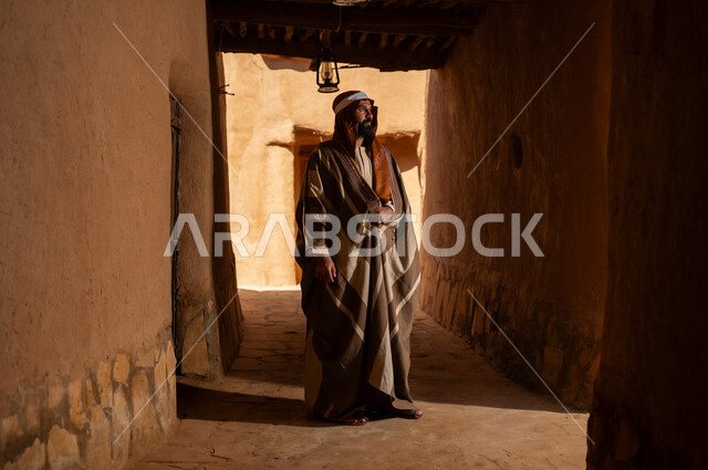 An Arab Saudi Gulf man wearing the founding day attire stands inside a mud building, commemorating the establishment of the first Saudi state by Imam Muhammad bin Saud, on the day we began, February 22, 1727. The historical and cultural depth of the Kingdom is the identity of Saudi National Day 92.