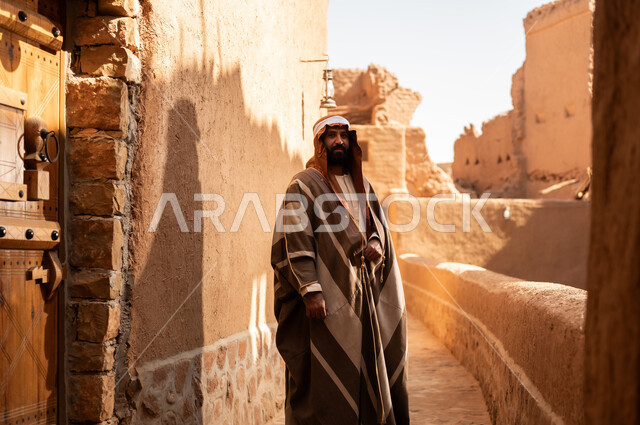 رجل عربي سعودي خليجي يرتدي زي يوم التأسيسي يقف وقفة شموخ وفخر بتاريخ المملكة, ذكرى تأسيس الدوله السعوديه الاولى على يد الامام محمد بن سعود, يوم بدينا 22 فبراير 1727م, العمق التاريخي والحضاري للمملكة، هوية اليوم الوطني السعودي 92