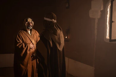 رجل كبير السن عربي سعودي خليجي يرتدي البشت وعقال يوم التأسيس يتحدث داخل مبنى طيني مع رجل, ذكرى تأسيس الدوله السعوديه الاولى على يد الامام محمد بن سعود, يوم بدينا 22 فبراير 1727م, العمق التاريخي والحضاري للمملكة، ارتداء الأزياء التقليدية تعكس التراث