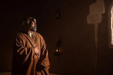 رجل كبير السن عربي سعودي خليجي يرتدي البشت وعقال يوم التأسيسيقف يجانب شباك داخل مبنى طيني , ذكرى تأسيس الدوله السعوديه الاولى على يد الامام محمد بن سعود, يوم بدينا 22 فبراير 1727م, العمق التاريخي والحضاري للمملكة، ارتداء الأزياء التقليدية تعكس التراث