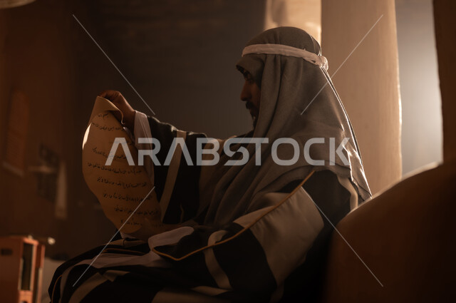 ارتداء الأزياء التقليدية تعكس التراث, رجل عربي سعودي خليجي يرتدي زي التأسيس يقرأ لفافة ورقية قديمة, ذكرى تأسيس الدوله السعوديه الاولى على يد الامام محمد بن سعود, يوم بدينا 22 فبراير 1727م, العمق التاريخي والحضاري للمملكة