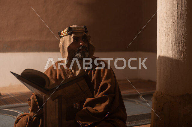 Wearing traditional attire reflects heritage. An elderly Arab Saudi Gulf man wearing a bisht and agal on Founding Day reads the Holy Quran, commemorating the establishment of the first Saudi state by Imam Muhammad bin Saud, on the day we began, February 22, 1727 AD, the historical and civilizational depth of the Kingdom.
