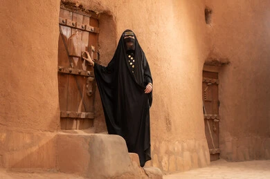 ارتداء الزي الشعبي في ذكرى تأسيس الدولة السعودية الاولى 22 فبراير، الفخر والاعتزاز بالهوية الوطنية، نمط حياة البدو الشعبية في البيوت الطينية التراثية، يوم بدينا 1727 م، امرأة عربية خليجية سعودية ترتدي العباءة السوداء والبرقع في منزل قديم