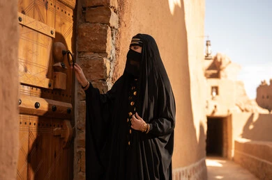 الفخر والاعتزاز بالهوية الوطنية، نمط حياة البدو الشعبية في البيوت الطينية التراثية، يوم بدينا 1727 م، ارتداء الزي الشعبي في ذكرى تأسيس الدولة السعودية الاولى 22 فبراير، امرأة عربية خليجية سعودية ترتدي العباءة السوداء والبرقع في منزل قديم