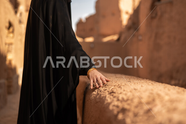شعار الهوية الوطنية وراية الإسلام والتوحيد، يوم بدينا 1727 م، ذكرى تأسيس الدولة السعودية الأولى 22 فبراير ، ارتداء الأزياء الشعبية التقليدية، البيوت الطينية التراثية القديمة، صورة مقربة لامرأة عربية خليجية سعودية ترتدي العباءة السوداء والبرقع