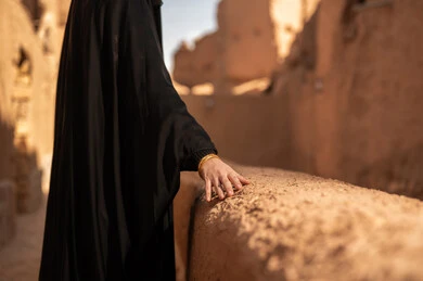 شعار الهوية الوطنية وراية الإسلام والتوحيد، يوم بدينا 1727 م، ذكرى تأسيس الدولة السعودية الأولى 22 فبراير ، ارتداء الأزياء الشعبية التقليدية، البيوت الطينية التراثية القديمة، صورة مقربة لامرأة عربية خليجية سعودية ترتدي العباءة السوداء والبرقع