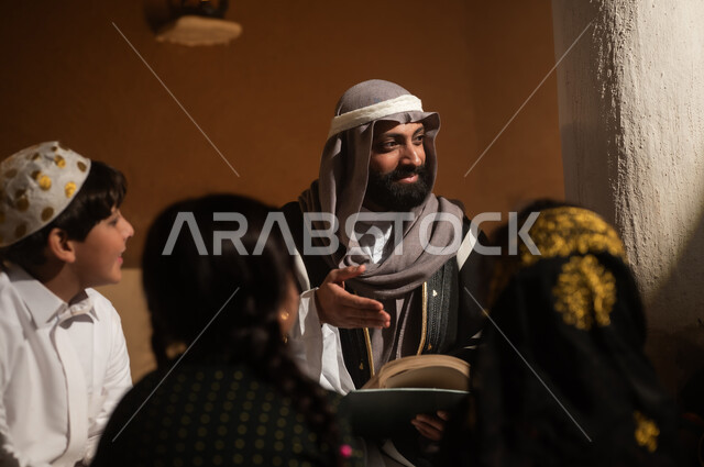 رواية قصة للابناء، الجلوس في احدى البيوت التراثية الطينية ،يوم بدينا 1727 م ، المحبة بين افراد الأسرة ،ذكرى تأسيس الدولة السعودية الأولى 22 فبراير ، رجل عربي خليجي سعودي يجلس مع أبنائه يرتدون الأزياء الشعبية في الأعياد الوطنية