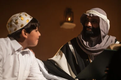 الجلوس في احدى البيوت التراثية الطينية ،يوم بدينا 1727 م ، رواية قصة للابناء، المحبة بين افراد الأسرة ،ذكرى تأسيس الدولة السعودية الأولى 22 فبراير ، رجل عربي خليجي سعودي يجلس مع ابنه يرتديان الأزياء الشعبية في الأعياد الوطنية