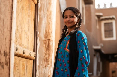 فتاة عربية خليجية سعودية ترتدي الزي التراثي تقف امام باب خشبي قديم, ذكرى تأسيس الدوله السعوديه الاولى على يد الامام محمد بن سعود, يوم بدينا 22 فبراير 1727م, العمق التاريخي والحضاري للمملكة، ارتداء الأزياء التقليدية تعكس التراث