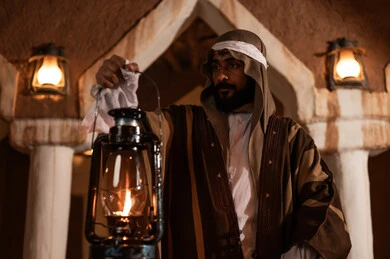 A holiday and national occasion, the anniversary of the establishment of the first Saudi state on February 22, expressing love and loyalty to the state and the homeland, an Arab Gulf Saudi man wearing traditional folk attire holding a lit lantern in his hand, pride and honor in national identity, the day we began in 1727 AD, a popular neighborhood with traditional clay houses.
