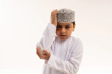 Omani Boy in Dishdasha Expressing Pain on White Background