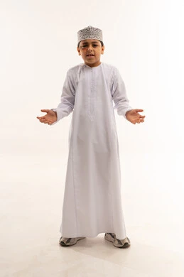 طفل عماني بالدشداشة والكمة التقليدية في الاستوديو