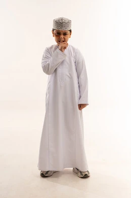 طفل عماني بالزي التقليدي يشير بعلامة الصمت