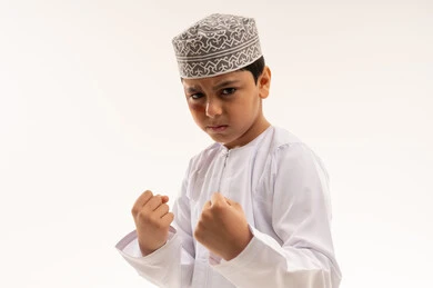 طفل عماني بالزي التقليدي في وضعية ملاكمة