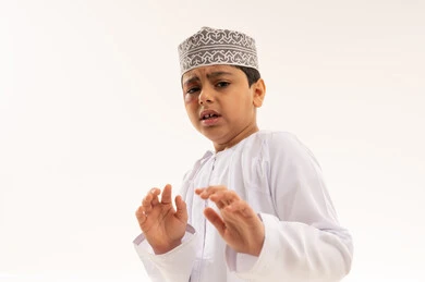 طفل عماني خائف بالزي التقليدي على خلفية بيضاء