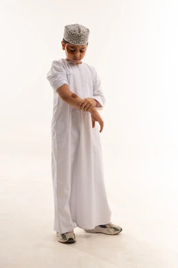 Omani Boy in Traditional Dress Examining Arm Injury