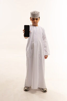 طفل عماني بالزي التقليدي يحمل هاتف ذكي