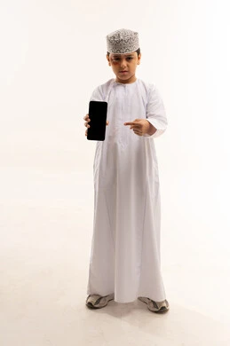 طفل عماني يحمل هاتفاً ذكياً على خلفية بيضاء