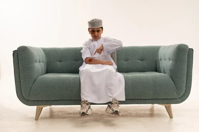 Omani Boy in Traditional Dress Angry on Green Sofa