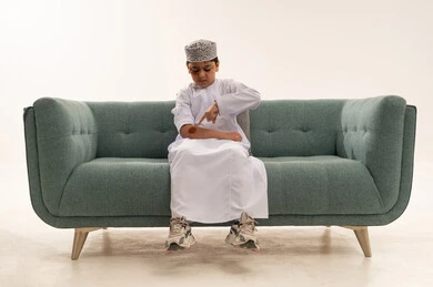 طفل عماني بالزي التقليدي يشير إلى إصابة بذراعه