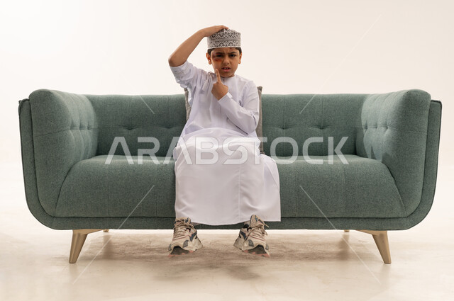 طفل عماني مصاب بكدمة في الوجه يجلس على أريكة