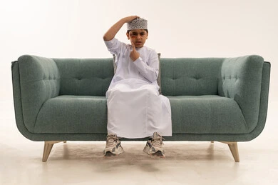 طفل عماني مصاب بكدمة في الوجه يجلس على أريكة